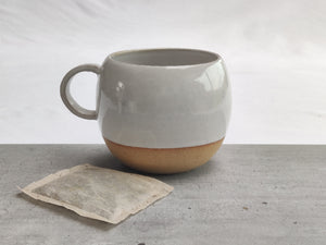 White round cup, tea cup, coffee cup. Unglazed base.