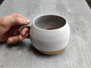 White round cup, tea cup, coffee cup. Unglazed base.